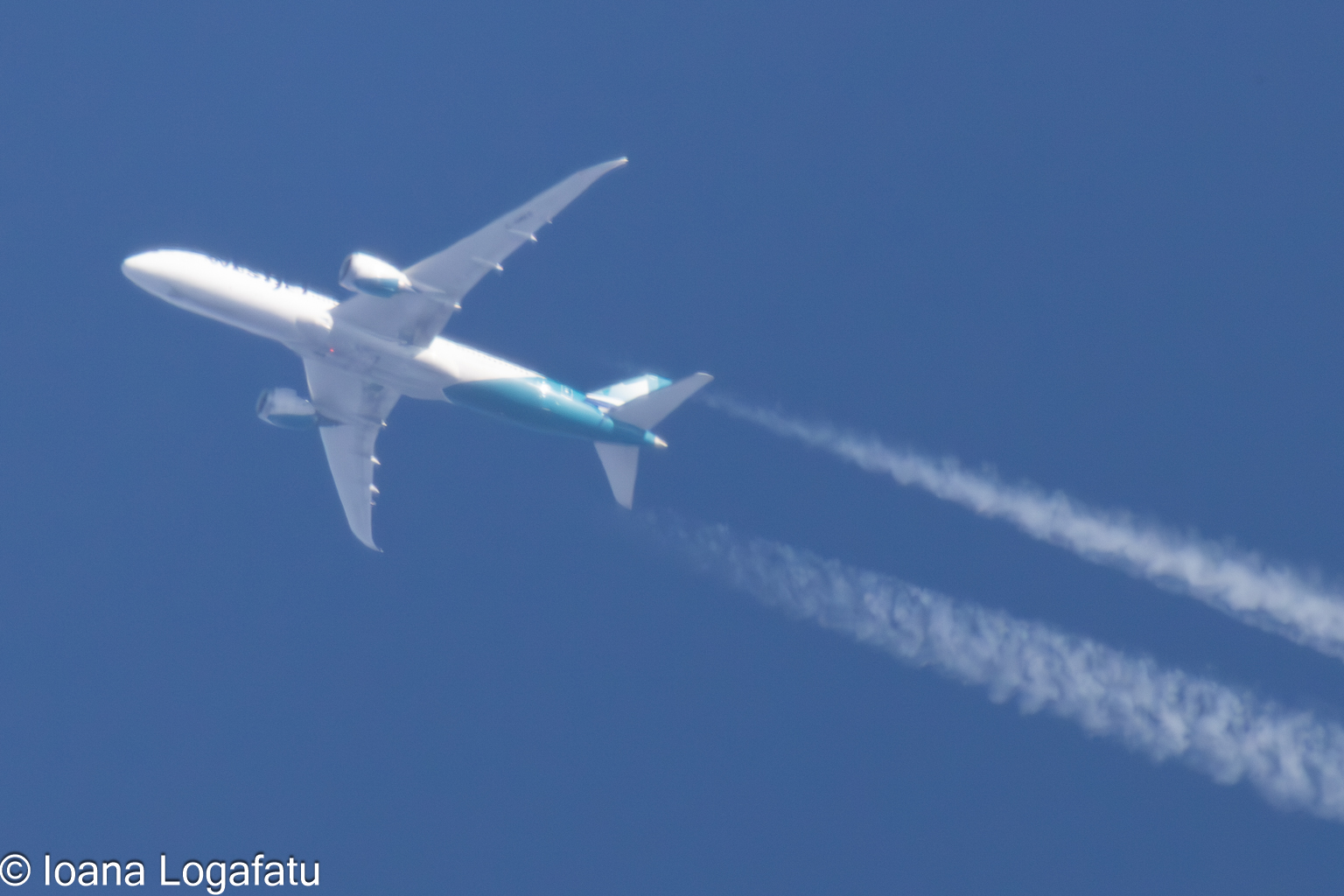 Jet soaring through a clear blue sky with trails